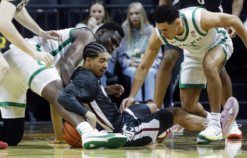 Washington State guard Myles Rice (2) fights for a loose ball against Oregon center N'Faly Dante (1), left, and Oregon guard Jackson Shelstad (3), right, during the second half of an NCAA college basketball game in Eugene, Ore., Saturday, Feb. 10, 2024. Washington State beat Oregon 62-56.(AP Photo/Thomas Boyd)