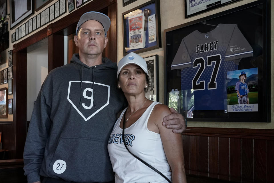 Padrig and Gina Fahey stand for a portrait next to a tribute to their son, Braden, in California, on Wednesday, Sept. 6, 2023. Braden, 12, collapsed at a football practice last August and died of a malformed blood vessel in the brain. The Faheys have read vicious comments from people who falsely blame vaccines for their son's death. They say seeing Braden’s memory being used and misrepresented by Robert F. Kennedy Jr. and others has been deeply painful. (AP Photo/Godofredo A. Vásquez)