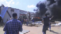 In this image made from video, people look on as a car factory burns in Mekele, Ethiopia, Wednesday, Oct. 20, 2021. Residents say new airstrikes have hit the capital of Ethiopia’s Tigray region as exclusive video shows injured people with bloodied faces being carried into ambulances. Ethiopia's government says it targeted facilities for making and repairing weapons, while a Tigray spokesman denies it. (AP Photo)