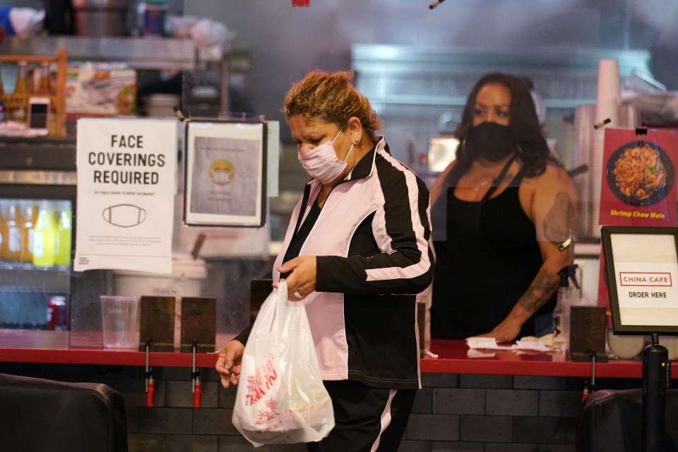 A customer picks up food at the Grand Central Market Monday, Nov. 16, 2020, in Los Angeles. California Gov. Gavin Newsom announced Monday, Nov. 16, 2020, that due to the rise of COVID-19 cases, Some counties have been moved to the state's most restrictive set of rules, which prohibit indoor dining. The new rules begin, Tuesday, Nov. 17. (AP Photo/Marcio Jose Sanchez)