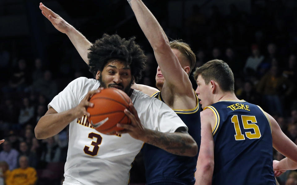 Minnesota's Jordan Murphy, left, tries to work around Michigan's Ignas Brazdeikis, center, and Jon Teske in the first half of an NCAA college basketball game Thursday, Feb. 21, 2019, in Minneapolis. (AP Photo/Jim Mone)