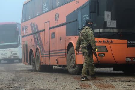 A rebel fighter stands near buses carrying people evacuated from the two villages of Kefraya and al-Foua, after an agreement reached between rebels and Syria's army, at insurgent-held al-Rashideen, Aleppo province, Syria April 14, 2017. REUTERS/Ammar Abdullah