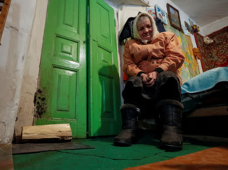 Retired school principal Nadiya Yurchenko, 79, warms herself by a stove in her neighbour's house in the village of Skryhalivka, Kiev region, Ukraine February 11, 2019. REUTERS/Gleb Garanich