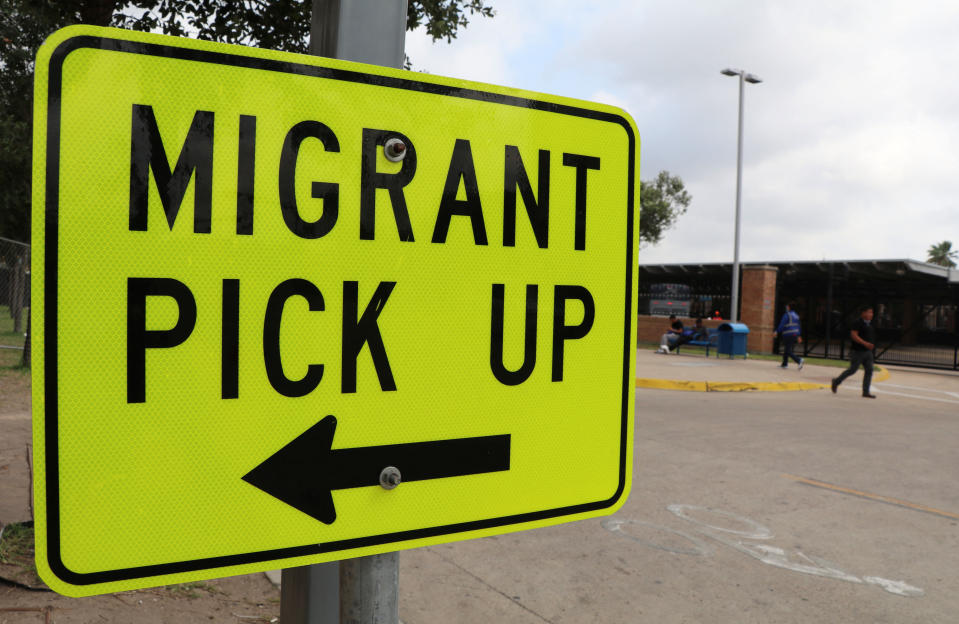 A sign on a broad street points to Migrant Pick Up, at La Plaza bus station.