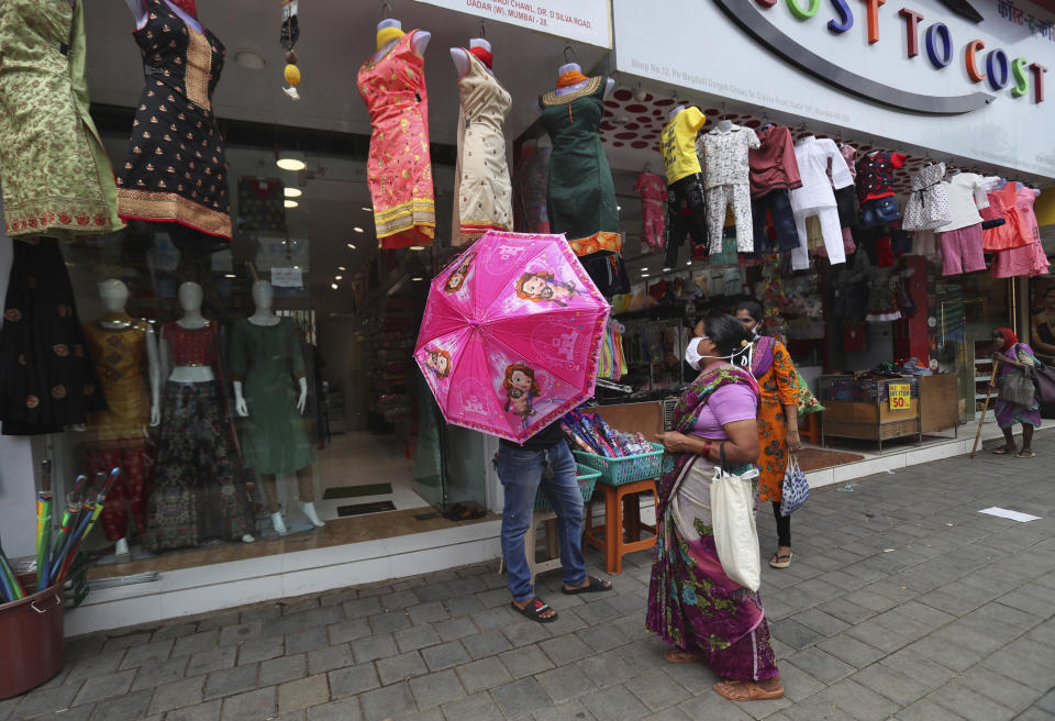 A roadside vendor tries to sell an umbrella to a customer in Mumbai, India, Monday, June 8, 2020. India is reopening its restaurants, shopping malls and religious places in most of its states after a more than 2-month-old lockdown even as the country continues to witness a worrying rise in new coronavirus infections. (AP Photo/Rafiq Maqbool)