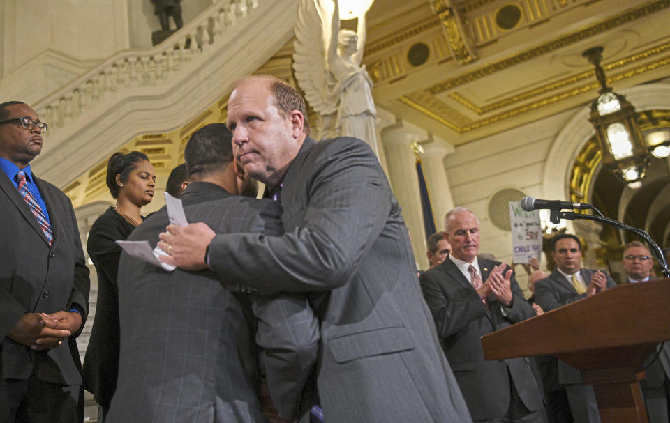 After announcing his support of legislation to change the statute of limitations on child sex abuse crimes, State Sen. Daylin Leach, a Montgomery County Democrat, facing camera, hugs Rep. Mark Rozzi, himself an abuse victim, at the state Capitol in Harrisburg, Pa., Monday, Sept. 24, 2018. A proposal to give victims of child sexual abuse a two-year window to sue over allegations that would otherwise be too old to pursue was overwhelmingly approved by the state House on Monday, as supporters cheered from the gallery. (Steve Mellon/Pittsburgh Post-Gazette via AP)