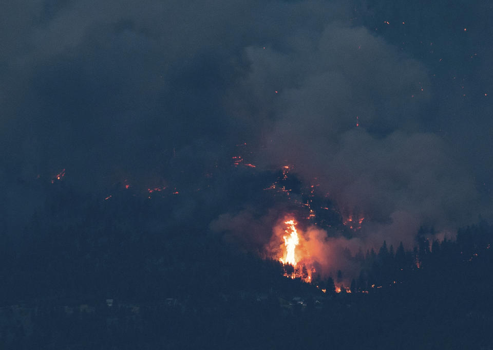 Flames leap into the air as a wider wildfire burns on the side of a mountain in Lytton, B.C., at dusk on Thursday, July 1, 2021. (Darryl Dyck/The Canadian Press via AP)