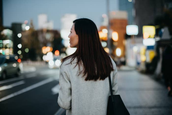 A young woman walking on city street at dusk