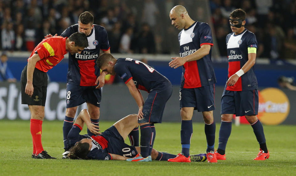 Paris Saint-Germain's Zlatan Ibrahimovic lies on the ground injured as his teammates and the referee look on during a Champions League quarterfinal first leg soccer match between Paris Saint-Germain and Chelsea at Parc des Princes stadium in Paris, Wednesday, April 2, 2014. (AP Photo/Michel Euler)