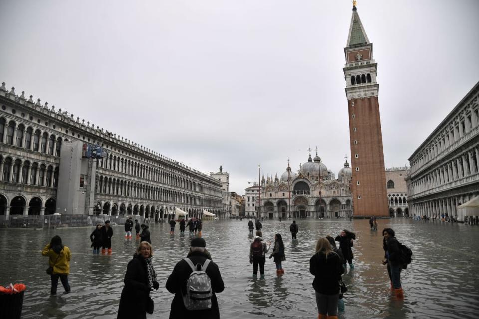 <div class="inline-image__caption"><p>Tourists and residents are forced to walk through several inches of water at the base of St. Mark’s Square leading into the narrow streets of the city. The square is normally filled with tourists feeding pigeons or sitting at sidewalk cafes that have all been closed due to historical flooding. </p></div> <div class="inline-image__credit">Marco Bertorello/Getty</div>