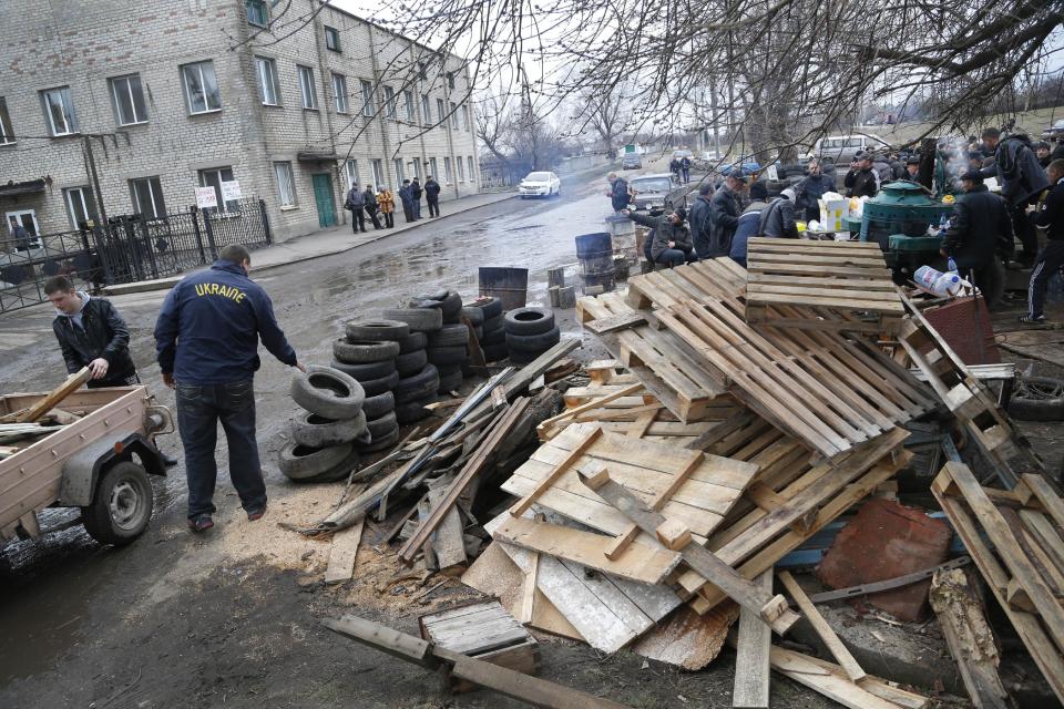 Pro Russian activists collect wood in their camp near the armory of Ukrainian army where they take a stand to prevent the export of arms and ammunition in the village of Poraskoveyevka, eastern Ukraine, Thursday, March 20, 2014. The disheveled men barricading the muddy lane leading into a military base in this eastern Ukraine village say they're taking a stand to defend Russian-speakers. (AP Photo/Sergei Grits)