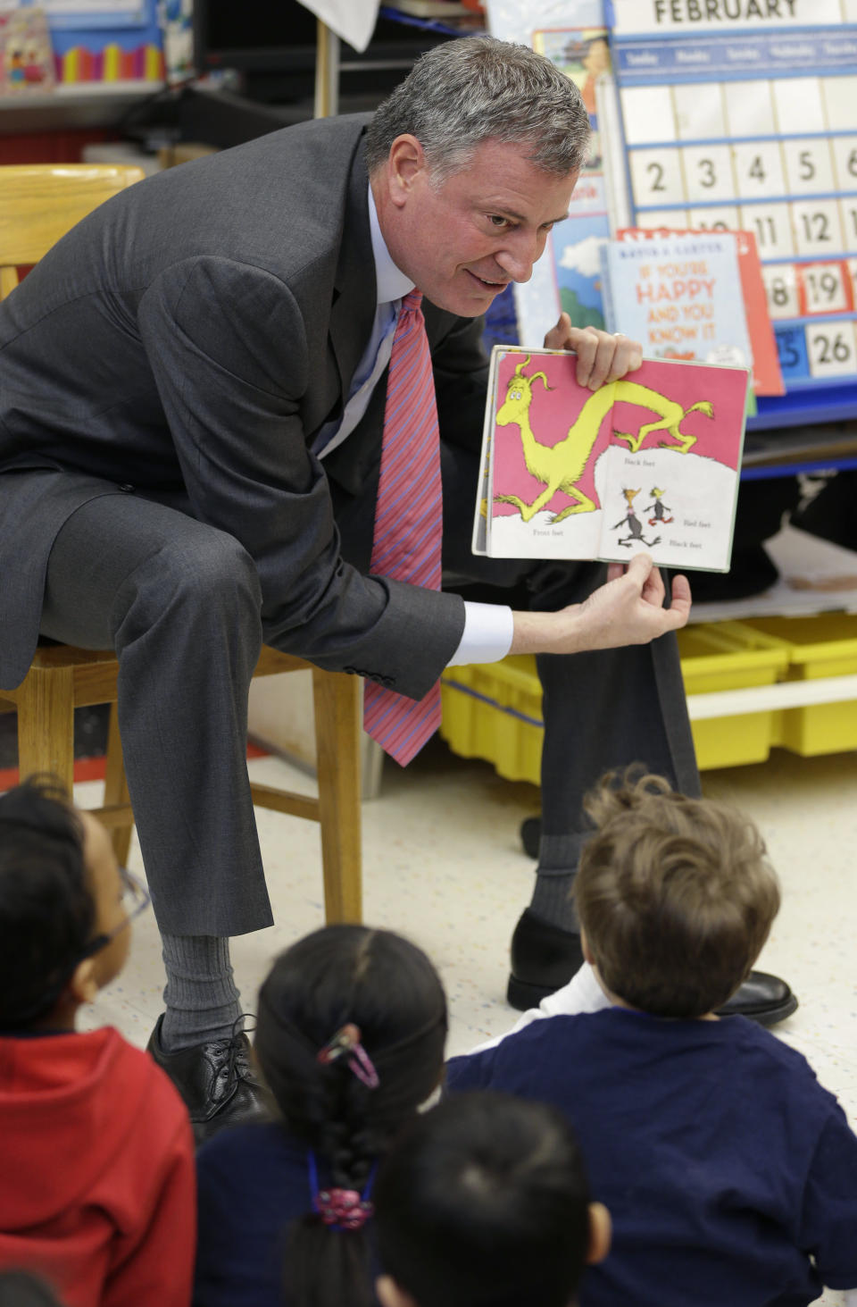 FILE - In this Feb. 25, 2014, file photo, New York City Mayor Bill de Blasio reads to children in a pre-kindergarten class at P.S. 130 in New York. De Blasio’s first 100 days as mayor of New York were marked in nearly equal measures by accomplishing campaign goals and committing political blunders. Most of his time and energy was devoted to a single issue, his central campaign promise to create universal pre-kindergarten and fund it with a tax on wealthy New Yorkers. That bruising fight resulted in a partial victory and defined de Blasio’s first months in office. (AP Photo/Seth Wenig, File)