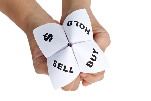 A person holds a paper displaying a dollar sign and the words buy, hold, and sell.