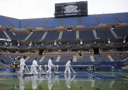 Workers squeegee the court in Arthur Ashe Stadium during a suspension of play at the 2014 U.S. Open tennis tournament in New York, August 31, 2014. REUTERS/Ray Stubblebine