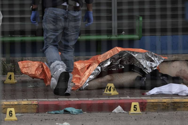 The body of a suspected attacker lies on the ground following a shooting incident in southern Israel, where at least two people died. Ilia Yefimovich/dpa