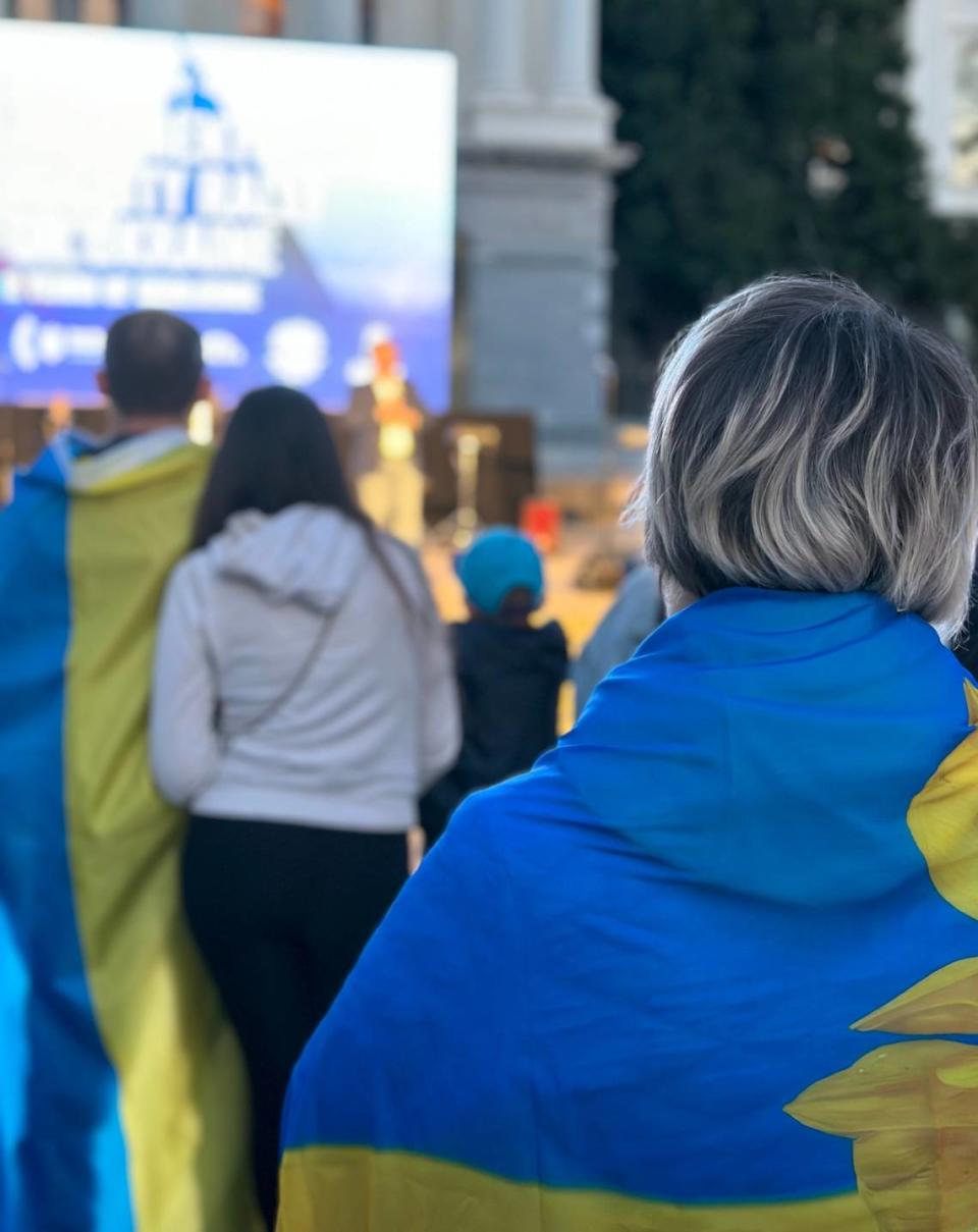 Ukraine supporters drape themselves in Ukrainian flags at an event at the state Capitol in Sacramento on Saturday marking the second anniversary of Russia’s invasion of Ukraine.