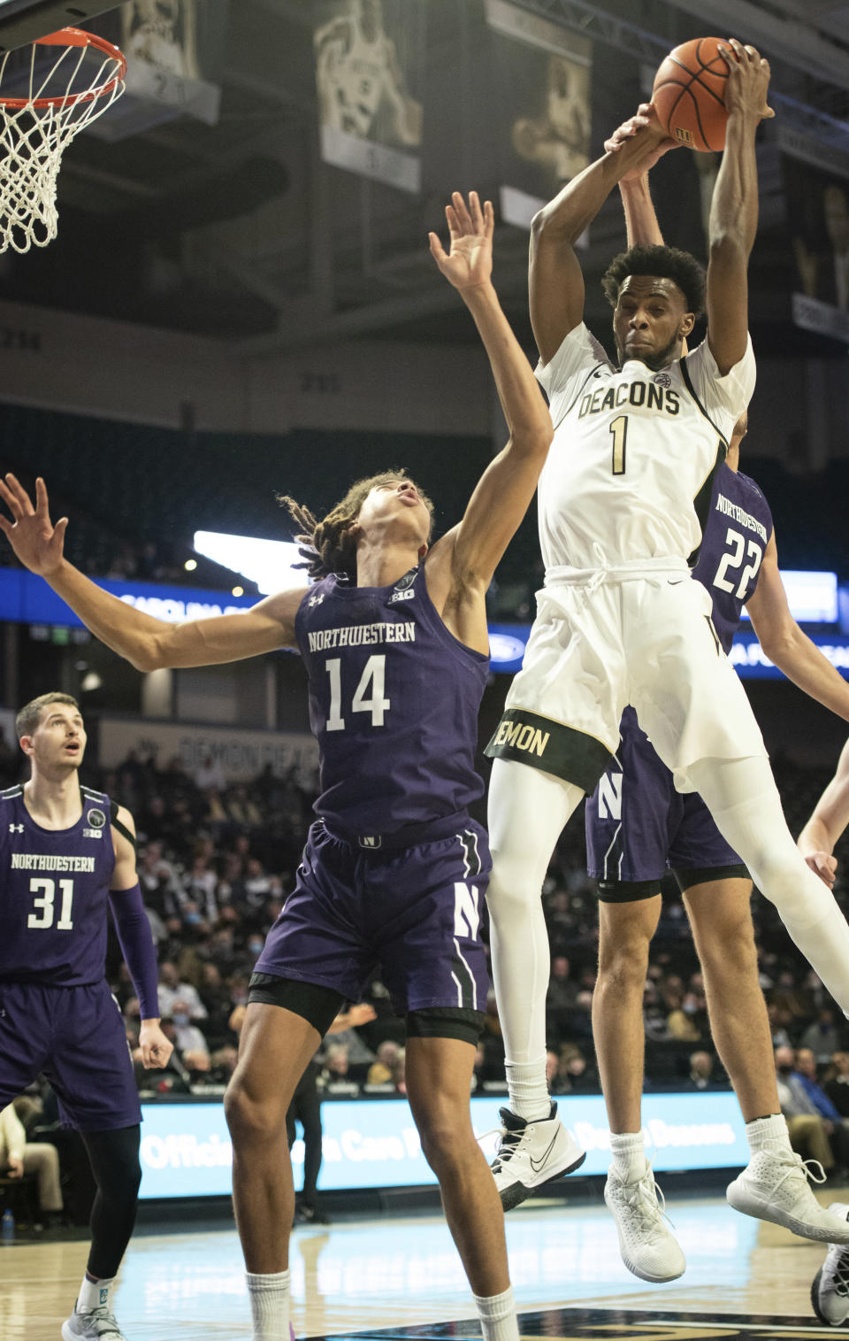 Wake Forest forward Isaiah Mucius (1) grabs a rebound over Northwestern guard Casey Simmons (14) in the first half of an NCAA college basketball game on Tuesday, Nov. 30, 2021, at the Joel Coliseum in Winston-Salem, N.C. (Allison Lee Isley/The Winston-Salem Journal via AP)