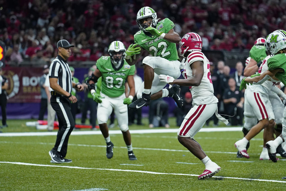 FILE - Marshall running back Rasheen Ali (22) leaps as he carries for a touchdown in the second half of the New Orleans Bowl NCAA college football game against Louisiana-Lafayette in New Orleans, Saturday, Dec. 18, 2021. Marshall coach Charles Huff announced Tuesday, Aug. 23, 2022, that Ali is taking an undisclosed leave of absence. (AP Photo/Gerald Herbert, File)