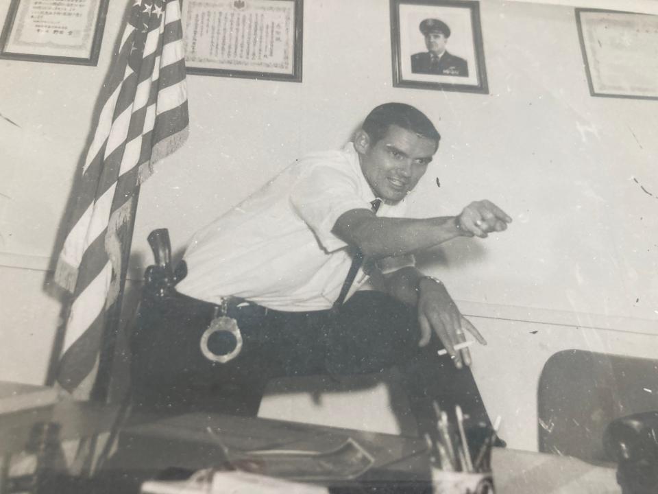 A photo of Winston Allen hangs on his wall, showing him at his desk in Kyushu, Japan, from his days as a special agent and Japanese linguist with the Air Force Office of Special Investigations in the 1960s.