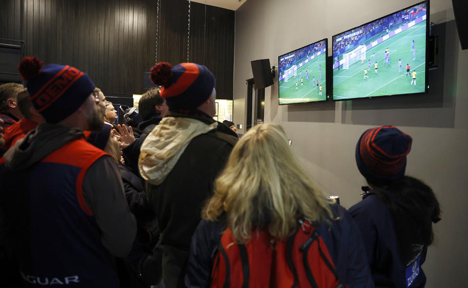 Fans watch the Matildas on screens in a bar at the MCG.