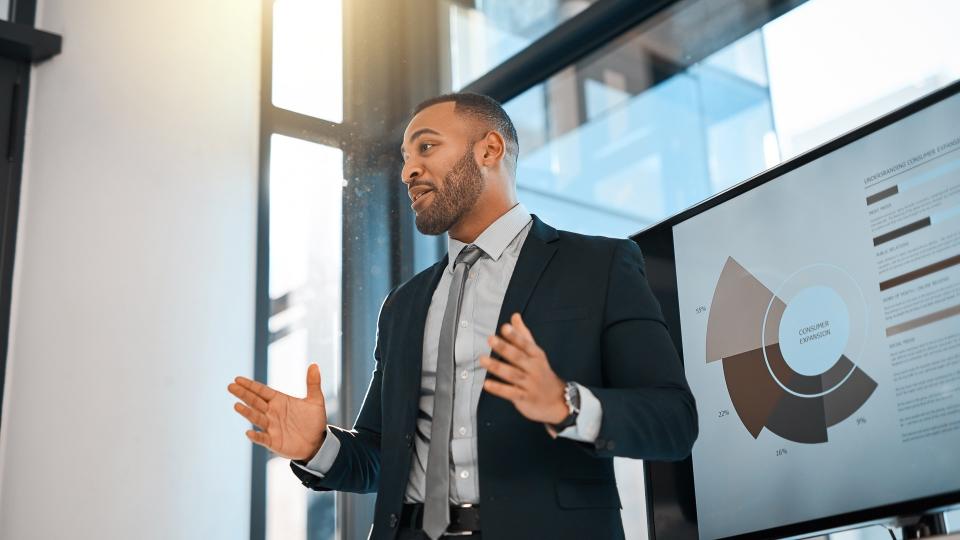 Shot of a young businessman presenting data on a screen during a meeting in an office.