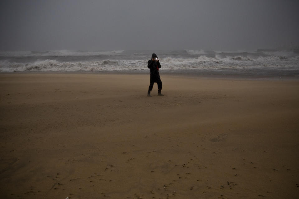 A woman takes photos at the beach during a storm in Barcelona, Spain, Tuesday, Jan. 21, 2020. A winter storm lashed much of Spain for a third day Tuesday, leaving 200,000 people without electricity, schools closed and roads blocked by snow as it killed four people. Massive waves and gale-force winds smashed into seafront towns, damaging many shops and restaurants. (AP Photo/Emilio Morenatti)