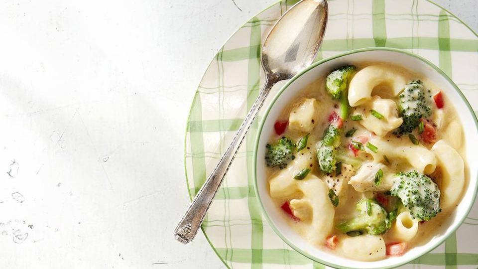 creamy mac and cheese chicken soup in a bowl with a spoon