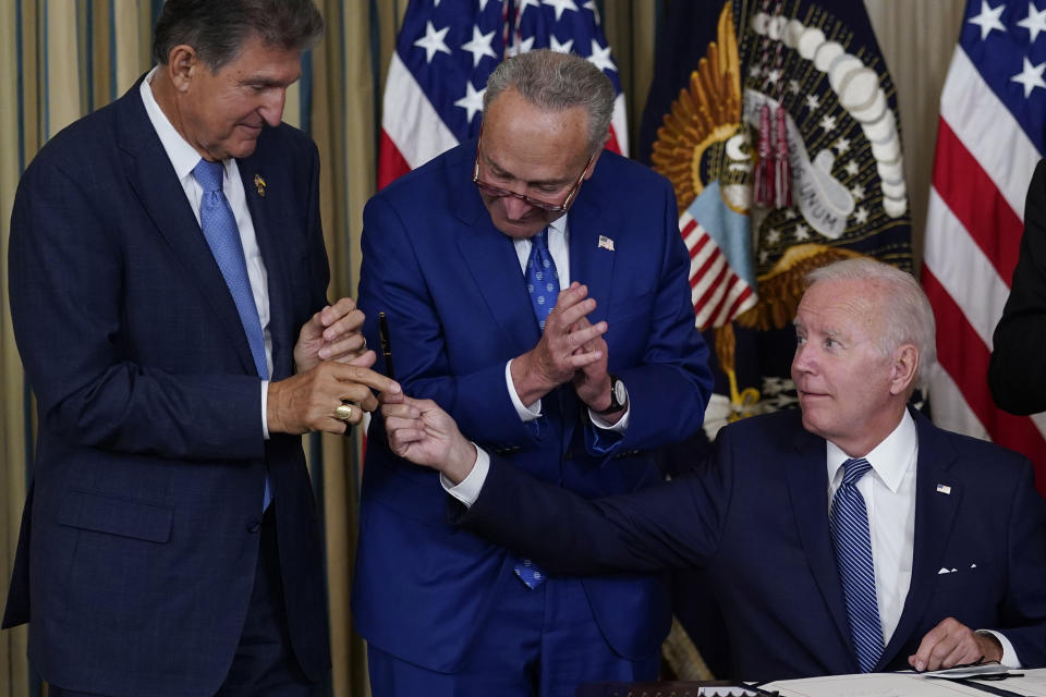 FILE - President Joe Biden hands the pen he used to sign the Democrats' landmark climate change and health care bill to Sen. Joe Manchin, D-W.Va., as Senate Majority Leader Chuck Schumer of N.Y., watches in the State Dining Room of the White House in Washington, Aug. 16, 2022. (AP Photo/Susan Walsh, File)