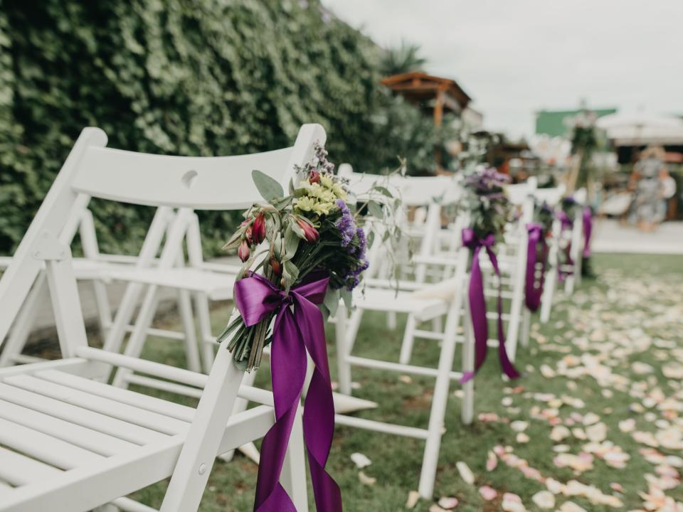 chairs at a wedding ceremony with florals tied on each outdoor wedding