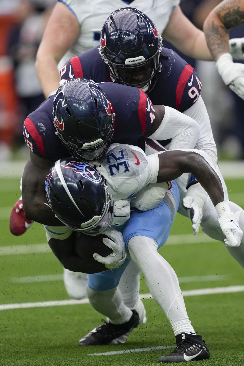 Tennessee Titans running back Tyjae Spears (32) is tackled for a loss of yards by Houston Texans linebacker Christian Harris (48) and defensive tackle Khalil Davis (94) during the first half of an NFL football game Sunday, Dec. 31, 2023, in Houston. (AP Photo/David J. Phillip)