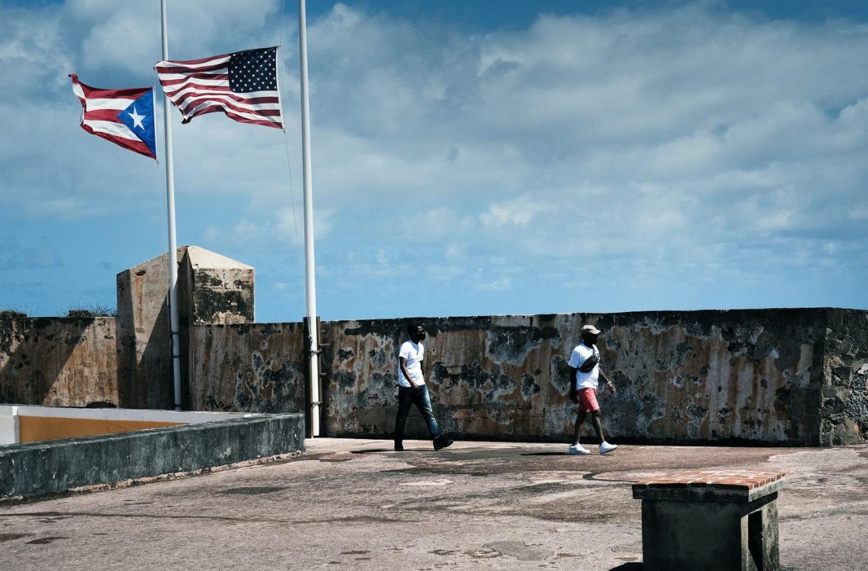 <span class="caption">In Old San Juan, Puerto Rico, the flags of the U.S. and its territory fly side by side.</span> <span class="attribution"><a class="link " href="https://www.gettyimages.com/detail/news-photo/people-walk-through-the-el-morro-national-monument-in-old-news-photo/1308296260" rel="nofollow noopener" target="_blank" data-ylk="slk:Spencer Platt/Getty Images;elm:context_link;itc:0;sec:content-canvas">Spencer Platt/Getty Images</a></span>