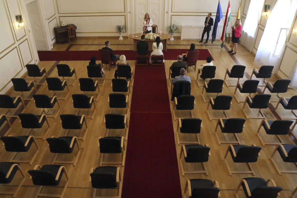 Groom Gyorgy David Jablonovszky and his bride Timea Jablonovszky attend their wedding ceremony along with their family members at the town hall of Miskolc, Hungary, Saturday, March 28, 2020. The couple celebrate today without wedding guests because of the government regulations to prevent the COVID-19 coronavirus pandemic. The new coronavirus causes mild or moderate symptoms for most people, but for some, especially older adults and people with existing health problems, it can cause more severe illness or death. (Janos Vajda/MTI via AP)