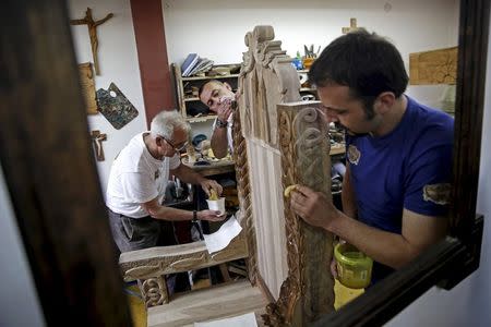 A reflection in a mirror shows Bosnian wood carver-sculptor Edin Hajderovac (R), his father Salem (L), and Munib Preldzic (C) working on a chair for Pope Francis, at his workshop in Zavidovici, Bosnia and Herzegovina, in this May 25, 2015 file photo. Even before arriving in Sarajevo, Pope Francis has achieved a remarkable feat. Preparing for the visit, Bosnians of all faiths are showing a rare unity in a country plagued by political and ethnic tensions nearly 20 years after the end of its 1992-95 war that claimed over 100,000 lives. While the pontiff's June 6 visit is the most eagerly awaited by Catholic Croats, the smallest group in the ethnically segmented state, Orthodox Serbs and Muslim Bosniaks have also taken an active part in preparing a warm welcome for Francis. REUTERS/Dado Ruvic/Files