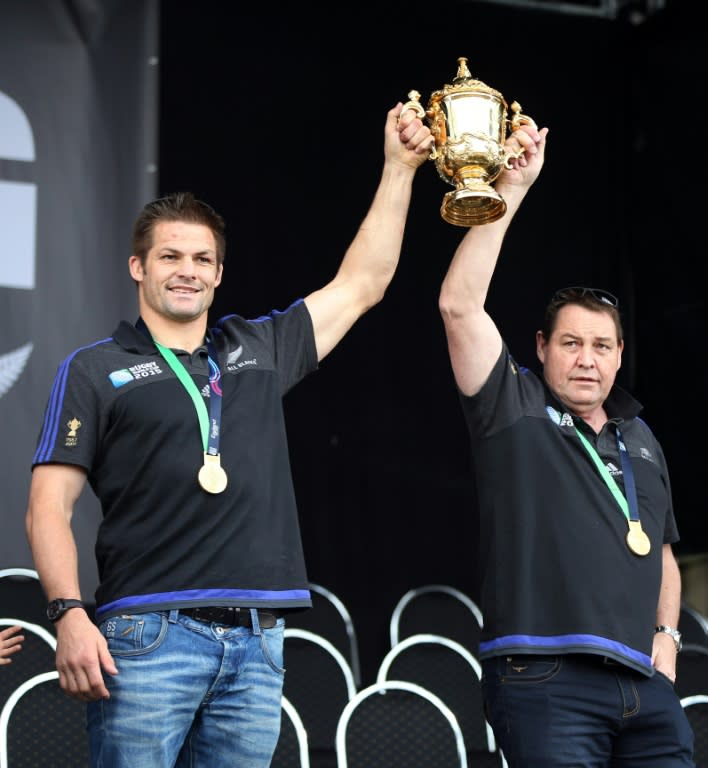 The All Blacks' captain Richie McCaw (L) and coach Steve Hansen hold the Rugby World Cup trophy at a parade and official welcome for the New Zealand team, in Auckland, in November 2015