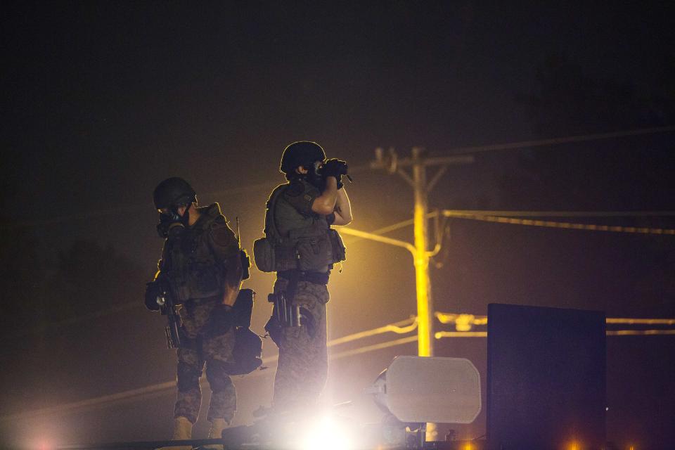 Police officers stand on top of an armored truck to monitor the movements of a rowdy group of demonstrators during protests in reaction to the shooting of Michael Brown near Ferguson, Missouri August 18, 2014. Police fired tear gas and stun grenades at protesters in Ferguson, Missouri on Monday, after days of unrest sparked by the fatal shooting of an unarmed black teenager by a white policeman. REUTERS/Lucas Jackson (UNITED STATES - Tags: CIVIL UNREST CRIME LAW SOCIETY)