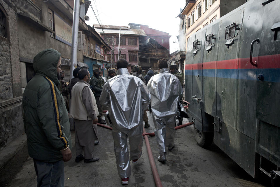 Indian firefighters walk towards the house where suspected militants were hiding during a gunbattle with Indian government forces in Srinagar, India, Wednesday, Oct. 17, 2018. Anti-India protests and clashes erupted in the main city of disputed Kashmir on Wednesday shortly after a gunbattle between militants and government forces killed at least two suspected rebels and a counterinsurgency police official. (AP Photo/Dar Yasin)