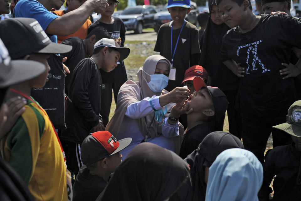 A boy receives drops of vaccine from a medical worker during a polio immunization campaign at Sigli Town Square in Pidie, Aceh province, Indonesia, Monday, Nov. 28, 2022. Indonesia has begun a campaign against the poliovirus in the the country's conservative province after several children were found infected with the highly-contagious disease that was declared eradicated in the country less than a decade ago. (AP Photo/Riska Munawarah)