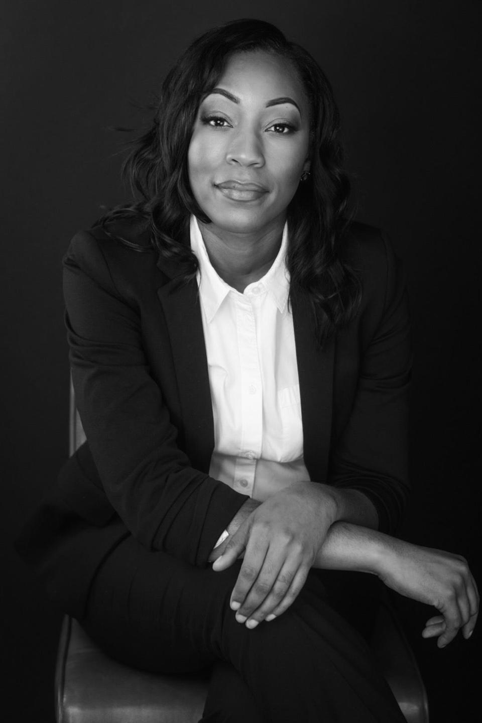 A black and white headshot of a woman wearing a white collars shift and black blazer