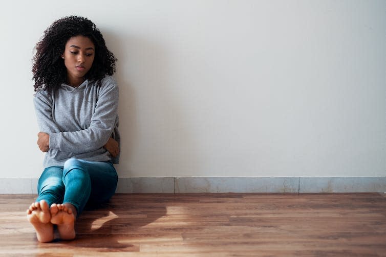 Woman sits alone barefoot on the floor