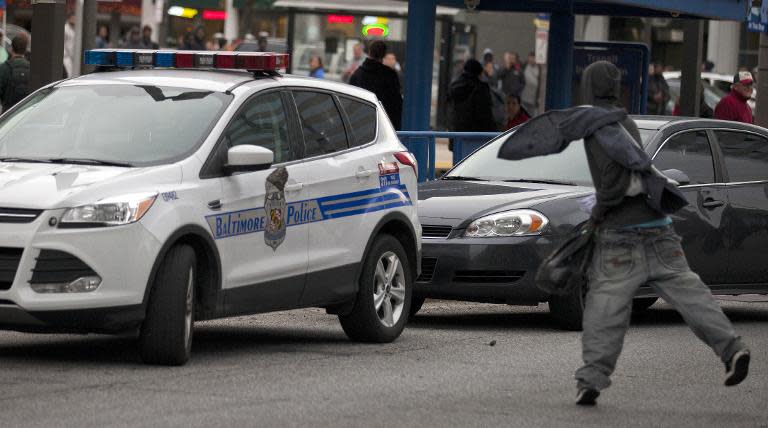 A protester throws a rock at a police car during a demonstration against the death of Freddie Gray while in police custody in Baltimore, Maryland, on April 25, 2015