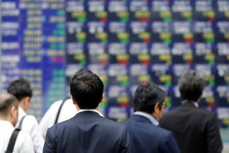 FILE PHOTO - People walk past an electronic stock quotation board outside a brokerage in Tokyo, Japan, September 22, 2017.   REUTERS/Toru Hanai