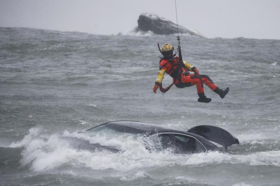 A coast guard diver is lowered from a helicopter to pull a body from the vehicle stuck near the brink of American Falls.