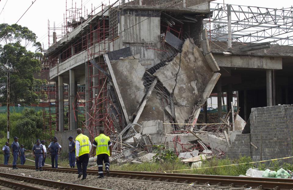 Policeman walk past a three-storey building that collapsed in the South African town of Tongaat