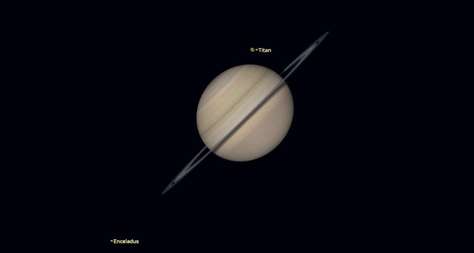 Saturn is slightly inclined, with the rings bisecting the gaseous body.  Just above the planet is the small moon Titan.  Far below to the left, Enceladus.