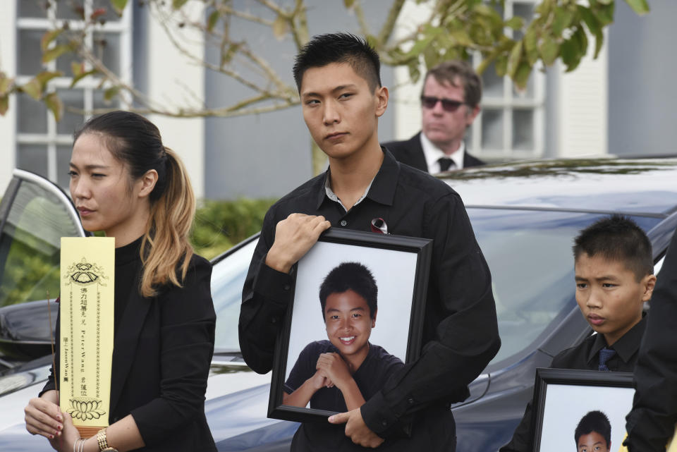 FILE - Jason Wang, center, holds a picture of his brother Peter, along with his younger brother, Alex, after his brother's funeral at Kraeer Funeral Home in Coral Springs, Fla., Peter Wang is a victim in the shooting at Marjory Stoneman Douglas High School. (Taimy Alvarez/South Florida Sun-Sentinel via AP, File)