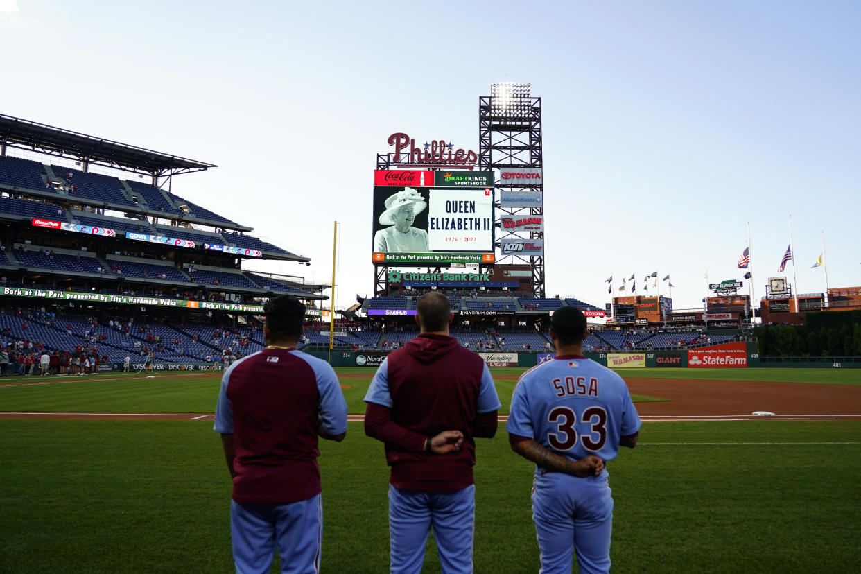 Philadelphia Phillies' players stand before a baseball game against the Miami Marlins for a tribute to Queen Elizabeth II, Britain's longest-reigning monarch who died after 70 years on the throne, Thursday, Sept. 8, 2022, in Philadelphia. (AP Photo/Matt Slocum)