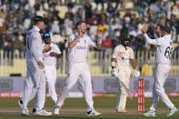 England's Ollie Robinson, center, celebrates with teammates after taking the wicket of Pakistan's Saud Shakeel, second right, during the third day of the first test cricket match between Pakistan and England, in Rawalpindi, Pakistan, Saturday, Dec. 3, 2022. (AP Photo/Anjum Naveed)