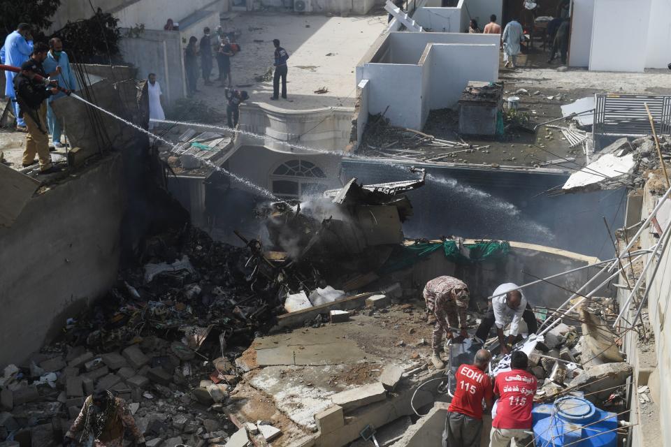 Police spray water on the part of a Pakistan International Airlines aircraft after it crashed at a residential area in Karachi on May 22, 2020. - A Pakistan passenger plane with more than 100 people believed to be on board crashed in the southern city of Karachi on May 22, the country's aviation authority said. (Photo by Asif HASSAN / AFP) (Photo by ASIF HASSAN/AFP via Getty Images)