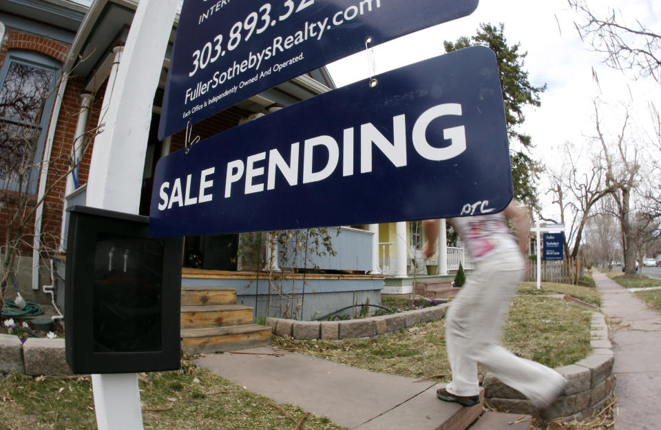 In this Saturday, March 17, 2012, photo, an unidentified woman passes by a pending sale sign outside home on the market in south Denver. A gauge of Americans who signed contracts to buy homes fell in April from nearly a two-year high in the previous month. The decline was the biggest in a year, but sales are still well ahead of last year's level for the same month, suggesting the housing market is improving slowly. (AP Photo/David Zalubowski)