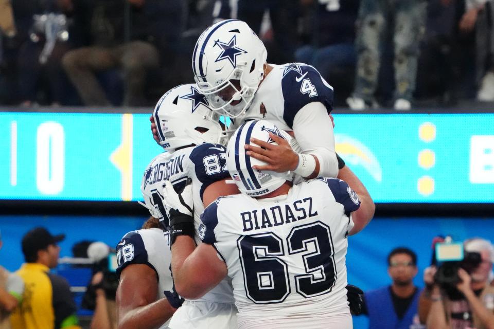 Dallas Cowboys quarterback Dak Prescott (4) celebrates with tight end Jake Ferguson (87) and center Tyler Biadasz (63) after scoring on an 18-yard touchdown run against the Los Angeles Chargers in the first half at SoFi Stadium.